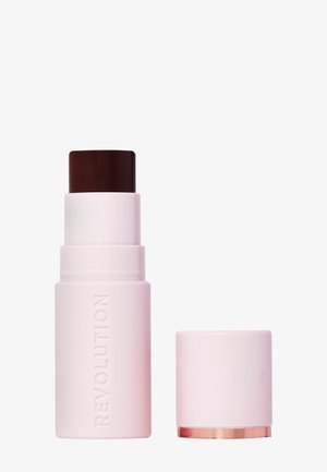 Revolution makeup stick i pink emballage med et mørkebrunt låg. Designet er cylindrisk med en glat overflade og et guldfarvet accent nederst.
