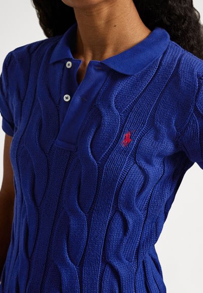Modra polo majica z rebrastim vzorcem in vzorcem pletenja s kabli, z ovratnikom in dvema gumboma, poudarjena z majhnim rdečim logotipom.