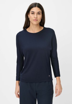 Chemise à manches longues bleu marine avec un col rond, en tissu doux. Dotée d'un petit logo près de l'ourlet et d'une coupe décontractée.