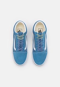 Modré semišové tenisky s bílými bočními pruhy. Mají multibarevné tkaničky v zelené a fialové barvě, bílé švy a zaoblenou špičku.