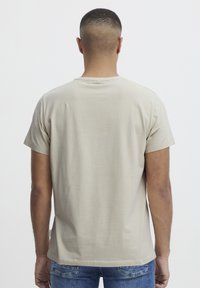 Beige kortermet t-skjorte med rund hals, laget av bomull. Bakdelen har en jevn tekstur uten mønstre eller synlig maskinvare.