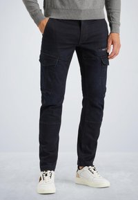 Donkerblauwe cargobroek van denim, voorzien van meerdere zakken, een rechte snit en subtiele stikdetails. Draag met witte sneakers.