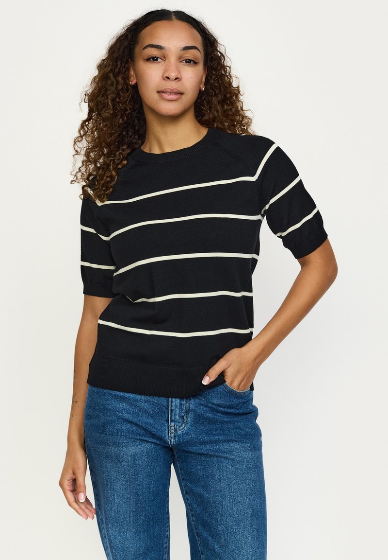 Črni pulover s kratkimi rokavi z belimi horizontale črtami, okrogel izrez in rebrast rob. Združen z modrimi džins hlačami.