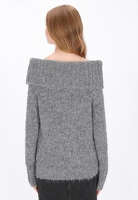 Szürke, vállnélküli pulóver puha kötött anyagból, bordázott gallérral és hosszú ujjal, laza szabással és texturált felülettel.