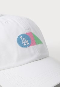 White baseball cap with embroidered circular logo in blue, featuring “LA”, and a pink and green triangular accent.