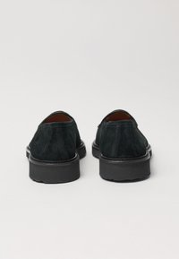 Black suede shoes with a low profile, round toe, and rubber sole. Features minimal stitching and a slightly textured upper.