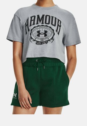Personne portant un t-shirt court gris Under Armour et un short vert foncé à cordon, les mains reposant sur les côtés.