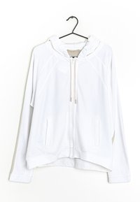 Haut à fermeture éclair blanc avec capuche, fabriqué en tissu doux. Il dispose de manches raglan, de poches kangourou et d'une coupe légèrement courte avec des accents beiges.