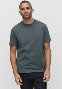 Mörkgrå kortärmad t-shirt, rund hals, gjord av bomull. Bärs med mörka jeans. Slät textur, kroppsnära passform. Enkel, utan mönster eller logotyper.