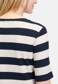 Navy and cream striped ribbed top with a wide neckline and short sleeves, featuring a smooth texture and relaxed fit.