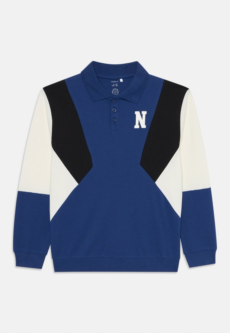 Modrá polo košeľa s dlhými rukávmi, má kontrastné čierne a biele uhlovité farebné bloky, trojbodový zapínací panel a biele logo "N".