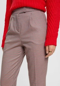 Rutig byxor med skräddarsydd passform, i en blandning av röda och svarta mönster. Materialet har en mjuk textur och sidofickor.