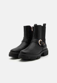 Mustad mustad ankle boots, mille modernne disain, külgse tasku, elastsete paneelide ja kuldse ringikujulise aktsendiga. Paksem kummitald.