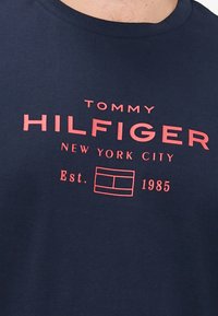 Granatowa bawełniana koszulka z różowym napisem graficznym "TOMMY HILFIGER NEW YORK CITY" oraz "Est. 1985." Okrągły dekolt.