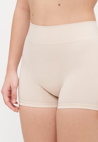 Béžové bezšvové šortky s vysokým pásom, vyrobené z elastického, hladkého materiálu a s mäkkým pásom, navrhnuté pre pohodlie a minimalistický vzhľad.