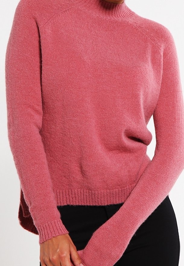 Pink, textured knit sweater with a high neckline, ribbed cuffs, and a slightly loose fit. Features drop shoulders and a longer back.