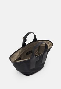 Borsa a tracolla nera con manici in pelle, fodera interna beige e tasca interna con zip, mostrata aperta su uno sfondo bianco.