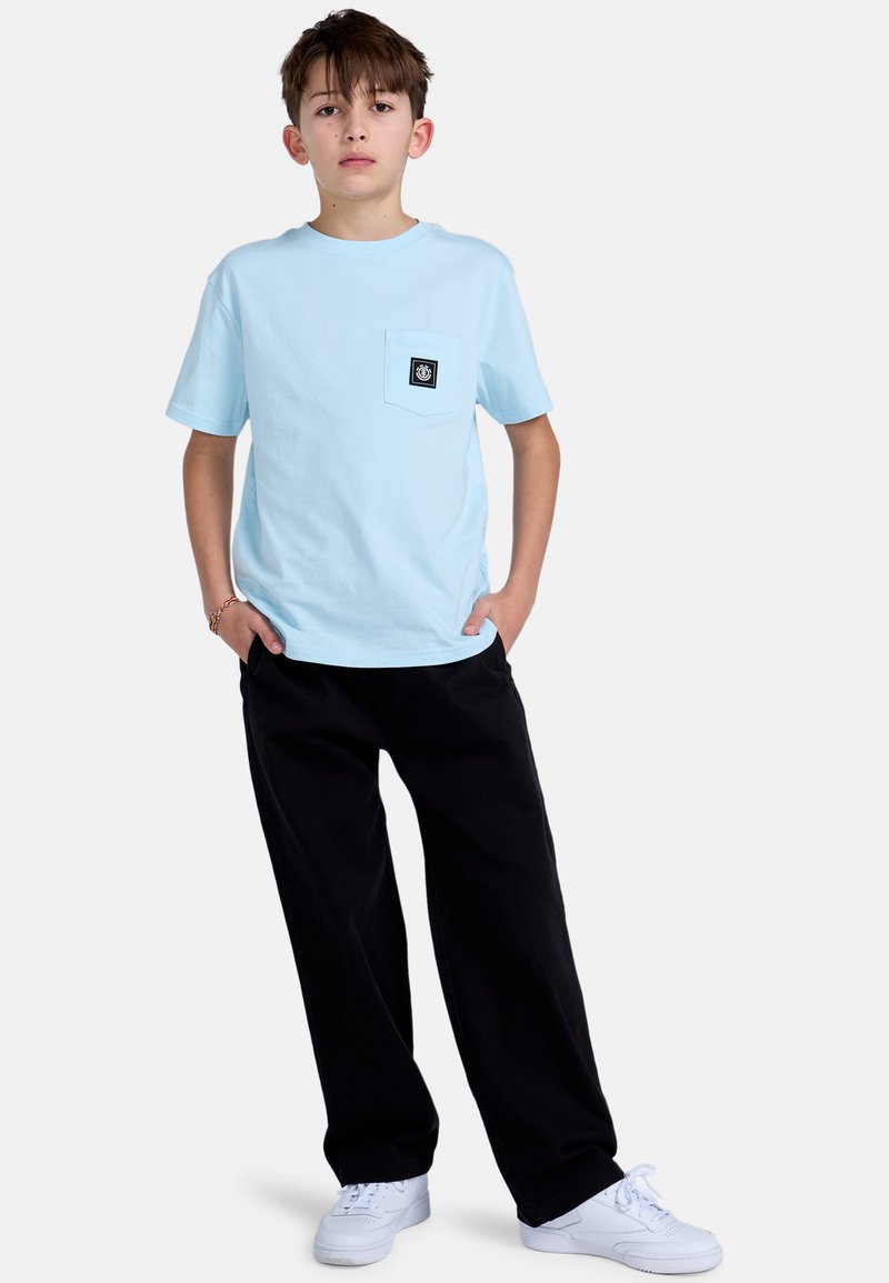 Lyseblå kortærmet T-shirt med brystlomme, parret med løse sorte bukser og hvide sneakers. Enkel design, bomuldsmateriale.