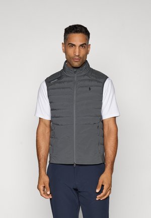 Gray puffer vest with a high collar, zip front, and side pockets. Worn over a white short-sleeve shirt. Subtle branding on the chest.