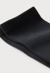 Ribbed fekete zoknik, puha anyagból készült, felül visszahajtott szegéllyel és sima felülettel a teljes hosszúságban.