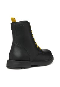 Stivaletti neri in pelle con lacci gialli e suola in gomma resistente. Presentano una punta rotonda e una linguetta gialla sul tallone.