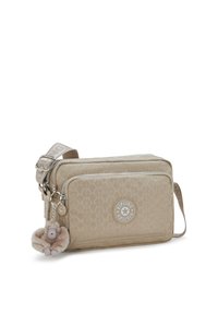 Beige crossbody bag with quilted pattern, zipper closures, and a circular logo. Features a plush monkey keychain accent. Adjustable strap included.