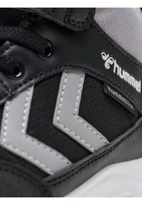 Czarne sneakersy z szarymi akcentami i wzorami w zygzak, wykonane z materiałów tekstylnych i skórzanych. Posiadają czarne sznurowadła i detal z logo.