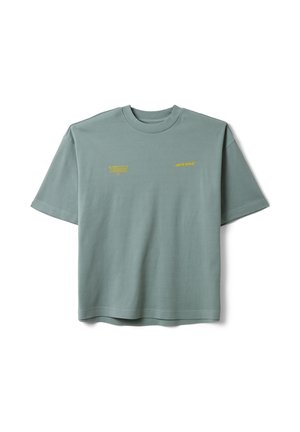 Kurzärmeliges salbeigrünes T-Shirt mit kleinen gelben Textlogos auf der Brust, eines mit der Aufschrift "dark wave" und das andere Blocktext.
