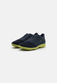 Scarpe sportive navy con tomaia in suede, lacci testurizzati e suola verde brillante. Design a punta arrotondata e dettagli di branding sottili.