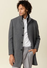 Abrigo de lana gris con un alto cuello, diseño de un solo botón y grandes botones negros. Presenta un ajuste entallado y una textura suave.