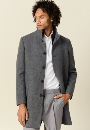 Cappotto in lana grigio con colletto alto, design monopetto e grandi bottoni neri. Presenta una vestibilità sartoriale e una texture liscia.