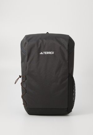 Black Terrex backpack with a smooth fabric surface, rounded shape, front zip pocket, side mesh pocket, and decorative cord detailing.