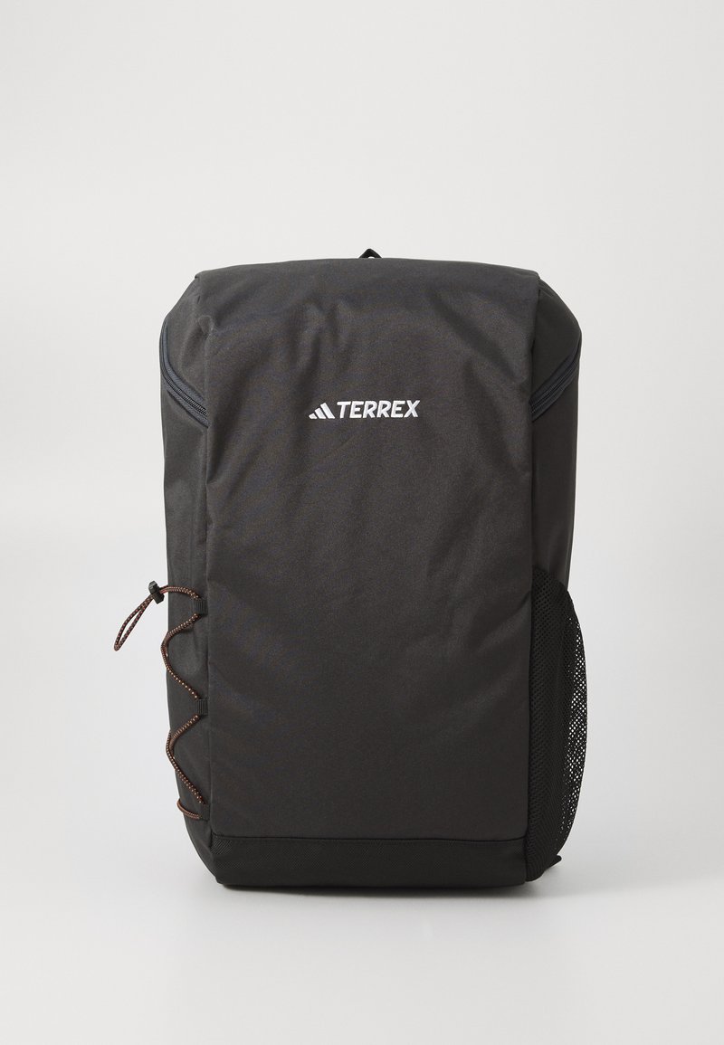 Black Terrex backpack with a smooth fabric surface, rounded shape, front zip pocket, side mesh pocket, and decorative cord detailing.
