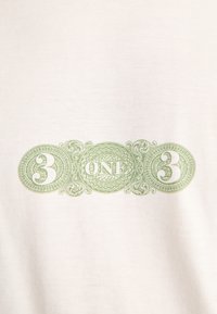Diseño verde ornamentado con el número 3 a ambos lados y la palabra UNO en el centro sobre un fondo de tela blanca.