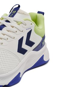 Hvidt atletikskos med mesh-overdel, marineblå accenter og logo, limegrøn hæl og tekstureret sål. Har snørelåsesystem.