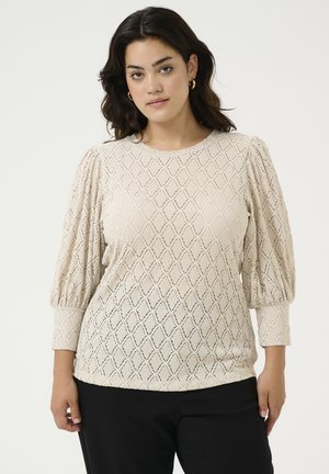 Beige gebloemde blouse met een diamanten patroon, textuurstof, geplooide mouwen en een ronde halslijn, gecombineerd met zwarte broek.
