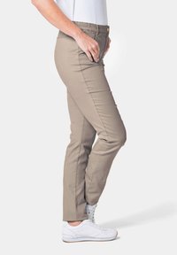 Beige broek met een elastische tailleband, slim-fit ontwerp en voorzakken. Gecombineerd met witte sneakers voor een casual uitstraling.