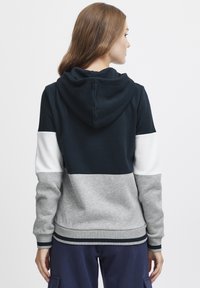 Sweatshirt à capuche présentant un design coloré avec des panneaux bleu foncé, blanc et gris. Fabriqué dans un tissu doux avec des accents et des poignets côtelés.