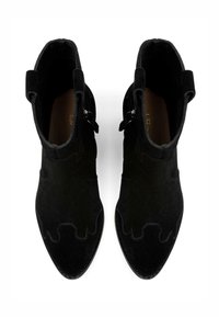 Stivali ankle in suede nera con punta affusolata, caratterizzati da dettagli di cucitura ondulata e cerniere laterali per una facile indossabilità. Foderatura interna liscia.