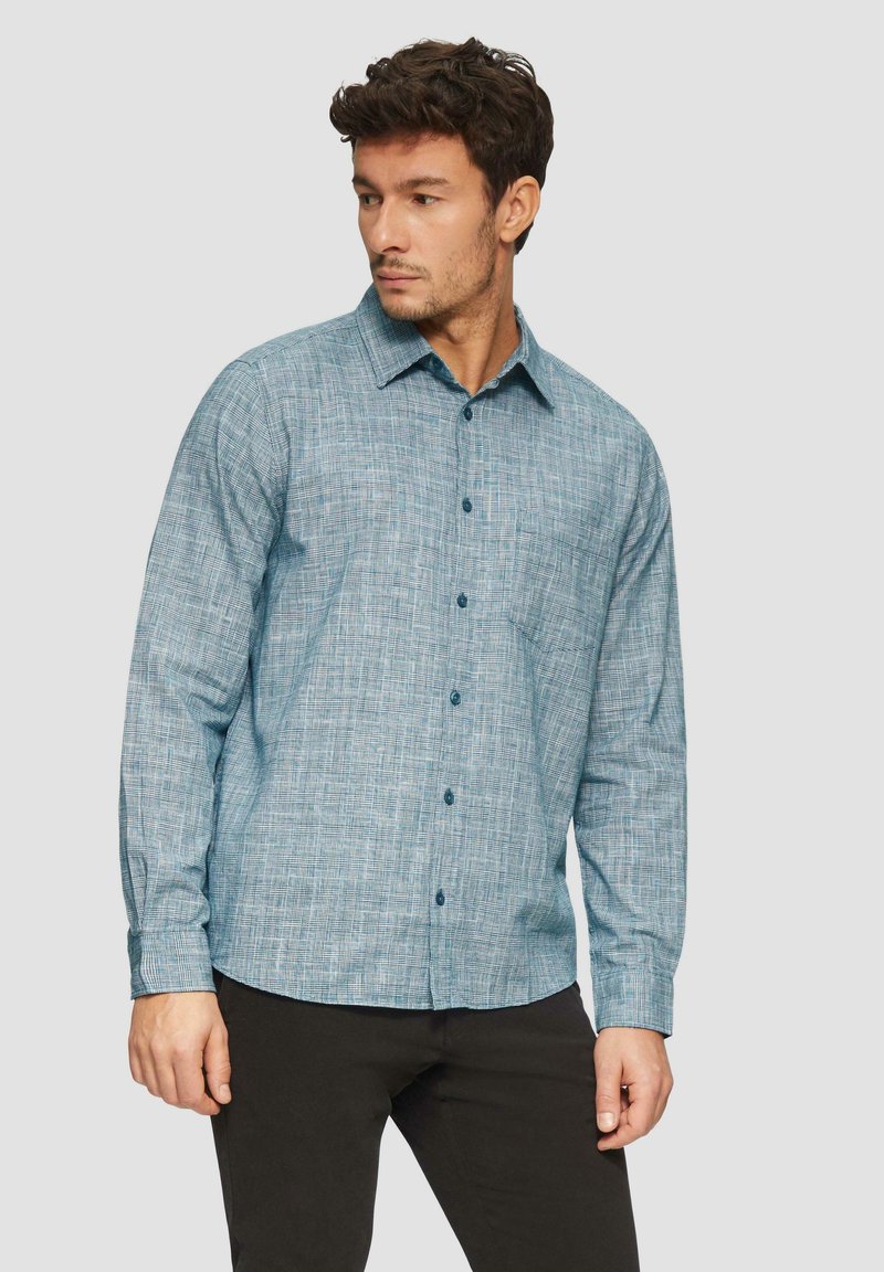 Lichtblauw overhemd met lange mouwen, voorzien van een textuurpatroon en een button-down kraag, gecombineerd met donkere broek. Inclusief knoopaccenten.