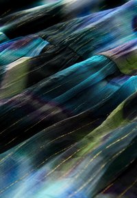 Robe fluide en noir, bleu, vert et violet avec des rayures verticales. Présente des coutures dorées et une texture douce et légère.
