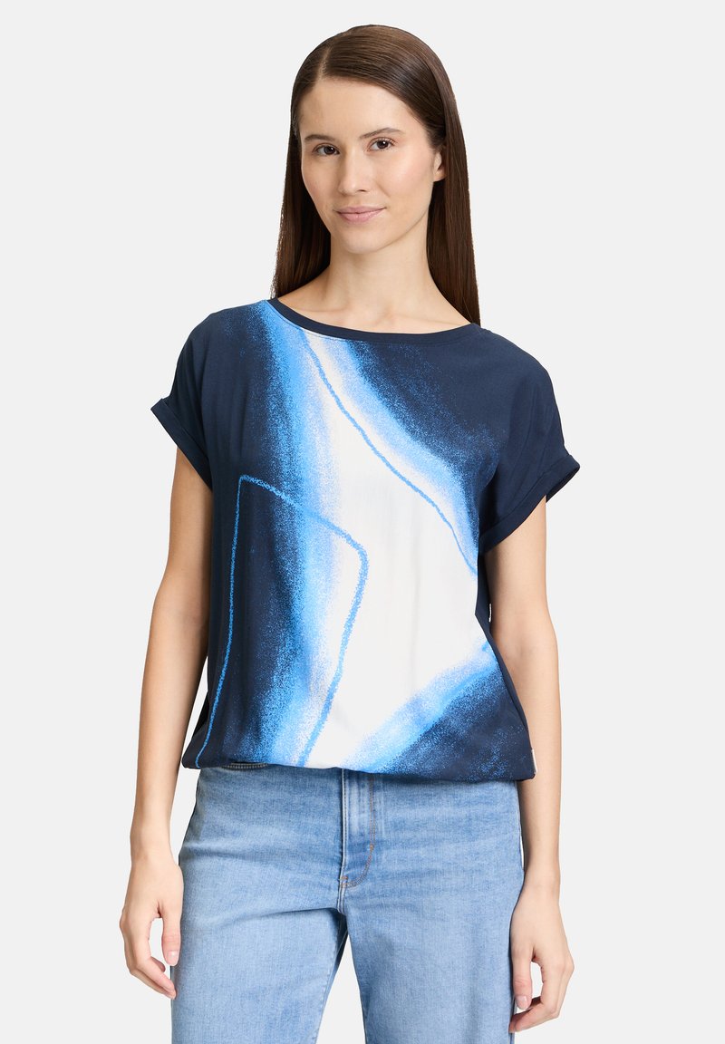 Granatowa bawełniana koszula z podwiniętymi rękawami, z abstrakcyjnym białym i niebieskim wzorem, luźny krój i miękka tekstura.