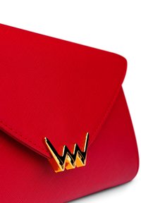 Červená kabelka typu clutch s texturovaným povrchem, na přední straně s akcentem v podobě zlatého a černého loga a trojúhelníkovým zavíráním.