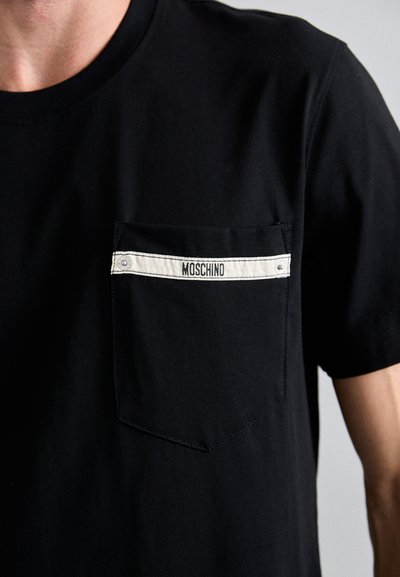 Fekete pamut póló, bal oldalon zsebfejléccel, fehér szalaggal és "MOSCHINO" logóval, rövid ujjakkal és kerek nyakkivágással.