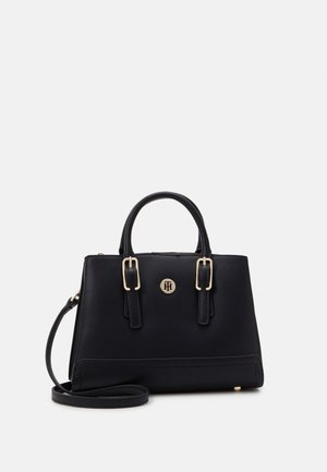 Czarna torebka o strukturalnym wzorze z podwójnymi górnymi uchwytami, złotymi sprzączkami, emblematem z logo oraz odpinanym paskiem na ramię na białym tle.