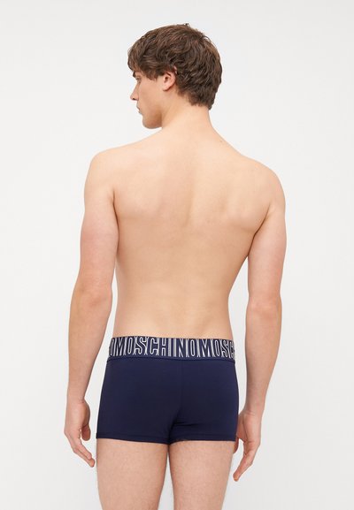 Tmavě modré boxerky s kontrastním logem na pasu. Tkanina vypadá hladce a elasticky, těsný design s krátkým pokrytím nohou.