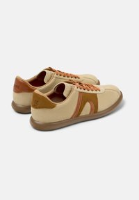beige mockaskor med bruna accenter, gummisulor, texturerad design och orange snören. Rundad tå och låg profil, avslappnad stil.