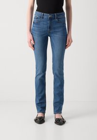 Jeans din denim albastru cu un design ajustat, talie medie și stil cu cinci buzunare. Prezintă cusături vizibile și un sistem de închidere cu buton.