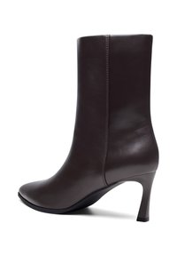 Ciemnobrązowy skórzany botek za kostkę z wąskim, średniej wysokości obcasem i gładkim, bezszwowym wykończeniem na białym tle.
