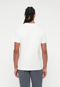 Tricou alb din bumbac, cu mâneci scurte, guler rotund și croială lejeră. Textură netedă, fără modele sau accente vizibile.